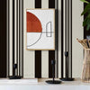 A framed artwork featuring an orange and white abstract design on a light background, displayed against a black and white str