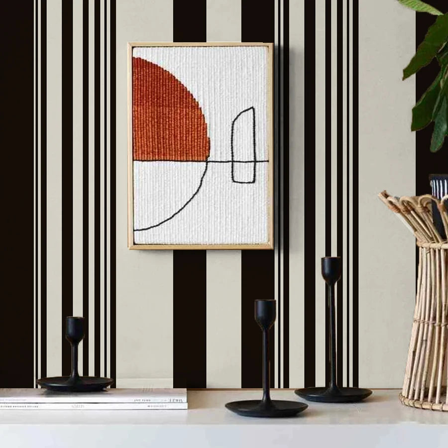 A framed artwork featuring an orange and white abstract design on a light background, displayed against a black and white str