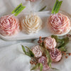 Three handmade pink peony silicone flower molds for candle, resin, and soap making displayed on a white tray.