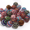 A pile of small resin rhinestone beads in various colors and two-tone stripes, set for crafting.