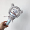 A hand holds a plush, gray, fuzzy cover for a light stick, which is attached to a silver-colored light stick.