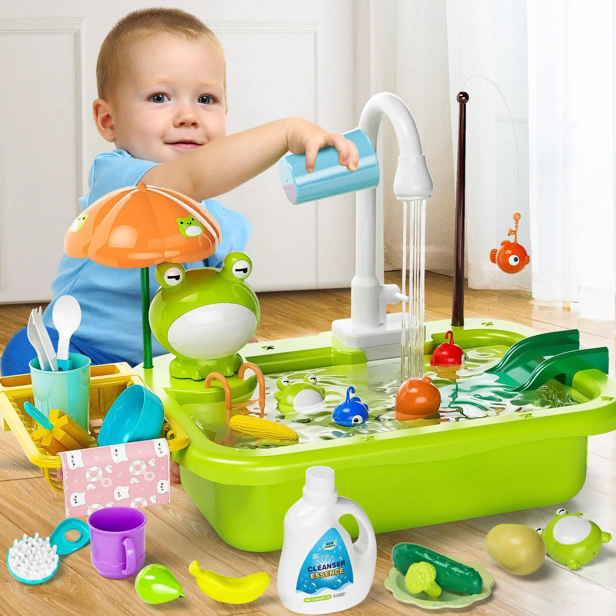 A toddler plays with a green electric kitchen sink set featuring running water, fishing toys, and food items.