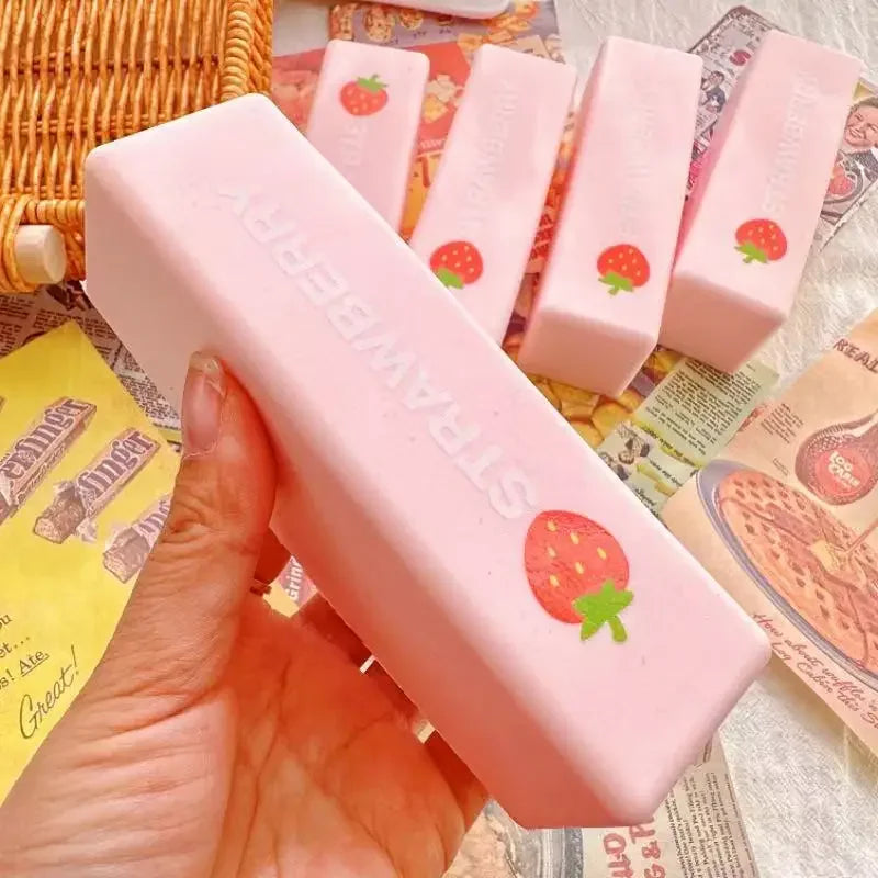 A hand holds a pink strawberry-themed fidget stick with a squeeze mechanism against a colorful background.