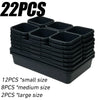 A stack of black modular drawer organizer trays with interlocking dividers in small, medium, and large sizes.