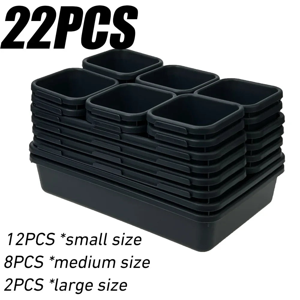 A stack of black modular drawer organizer trays with interlocking dividers in small, medium, and large sizes.