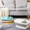 Un cubo de baño y spa plegable blanco reposa sobre un suelo gris estampado junto a un sofá.