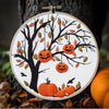 Cross stitch kit featuring an orange pumpkin tree design on a white background with embroidery tools.