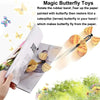 A hand holds a magic butterfly toy that rotates a rubber band to tear up paper and restore a butterfly.