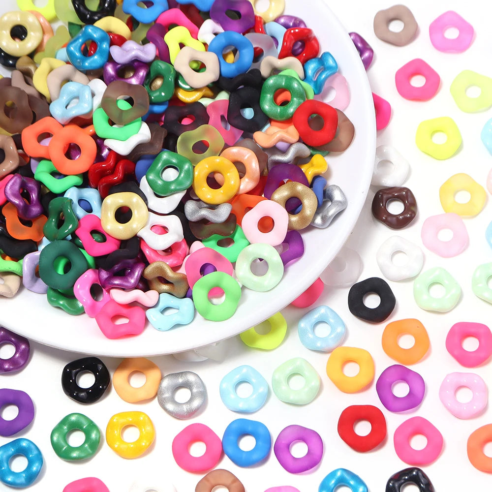 A close-up view of colorful acrylic spacer beads in various shapes and colors for jewelry making.