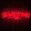 A neon sign spelling out THE WORLD IS YOURS in red light, hanging against a dark grid background.