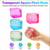 A hand holds four transparent square pinch music toys in various colors, demonstrating sensory squeezing and stress relief.