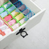 A white storage box filled with silicone toilet lids and lifters in various colors and patterns.