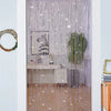A doorway decorated with a sheer purple curtain made of hanging glittery tassels and a framed artwork.