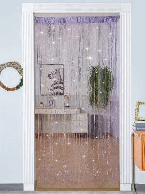 A doorway decorated with a sheer purple curtain made of hanging glittery tassels and a framed artwork.