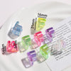 A collection of clear and colored acrylic alphabet beads for jewelry making displayed on a white plate.