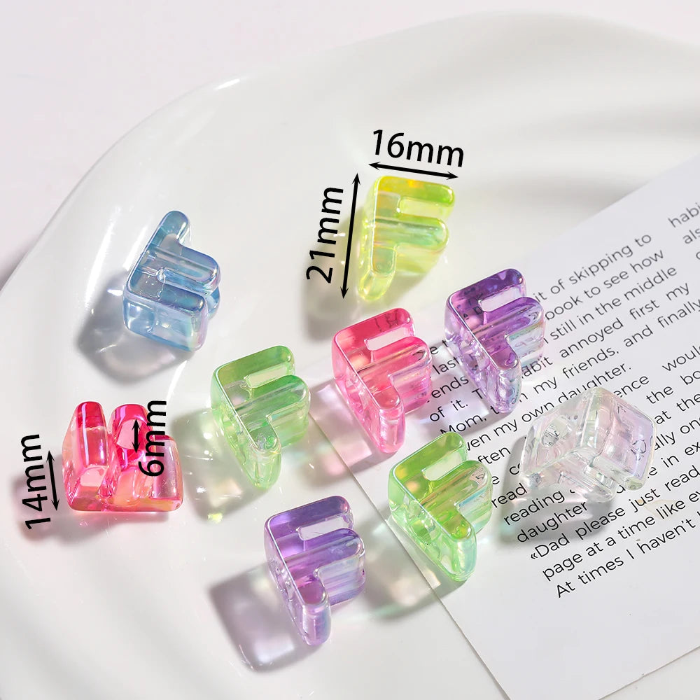 A collection of clear and colored acrylic alphabet beads for jewelry making displayed on a white plate.