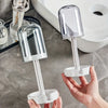 A hand holds a modern bathroom toothbrush holder with a dust cover and drainage, next to a white toilet.
