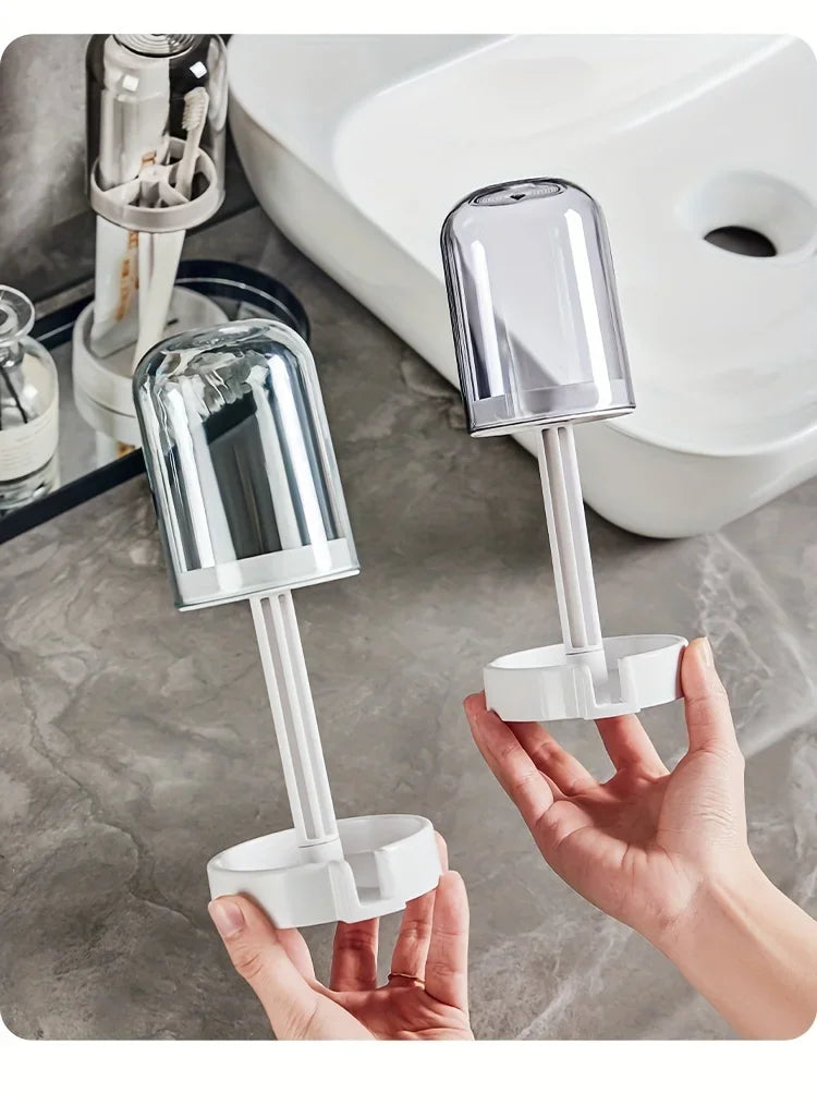 A hand holds a modern bathroom toothbrush holder with a dust cover and drainage, next to a white toilet.
