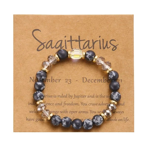 Perlenarmband mit dunkelgrauen und klaren Kristallperlen, präsentiert auf einer braunen Karte mit dem Sagittarius-Tierkreisze