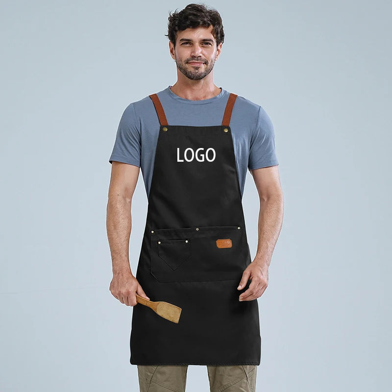 A man wearing a black waterproof kitchen apron with a logo and a wooden spatula.