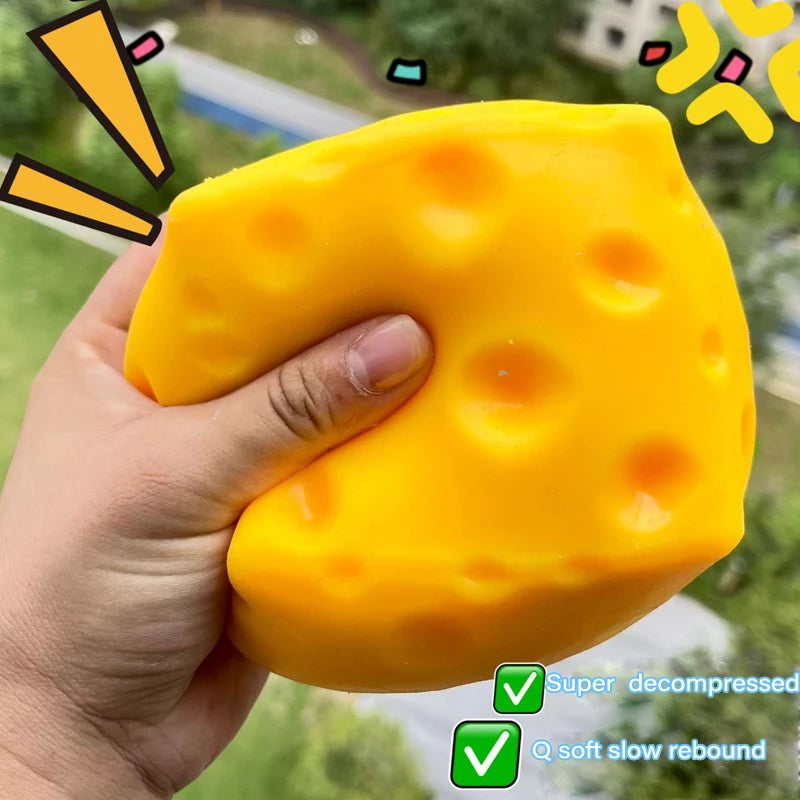 A hand holds a bright yellow cheese-themed squishy stress relief toy with a soft slow rebound.