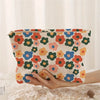 A hand holds a floral corduroy makeup bag with a secure zipper against a white background.