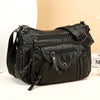 A black leather tote bag with a flap closure and adjustable strap is shown against a light background.