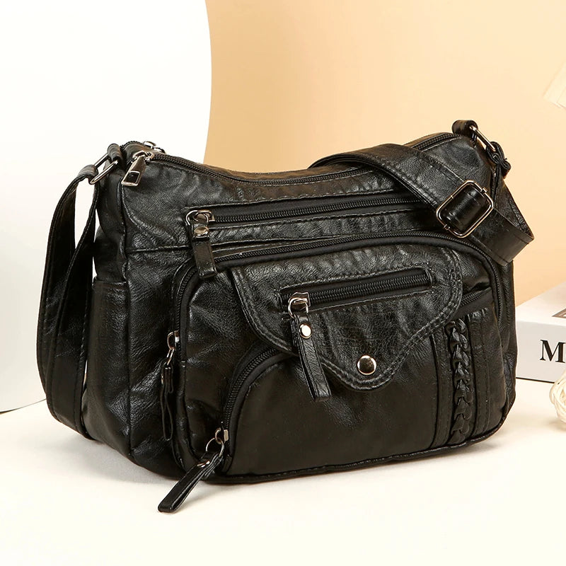 A black leather tote bag with a flap closure and adjustable strap is shown against a light background.