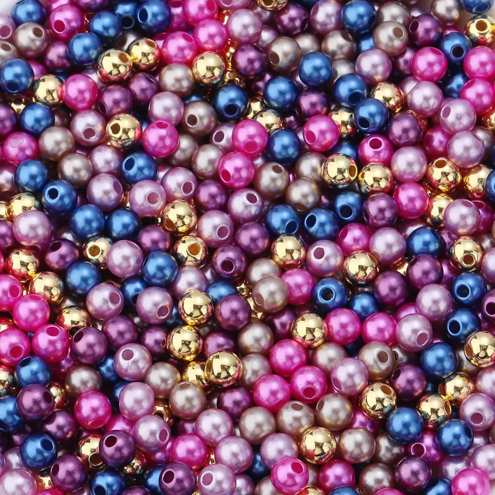 A close-up of numerous round imitation pearl beads in various shades of pink, purple, blue, and gold.
