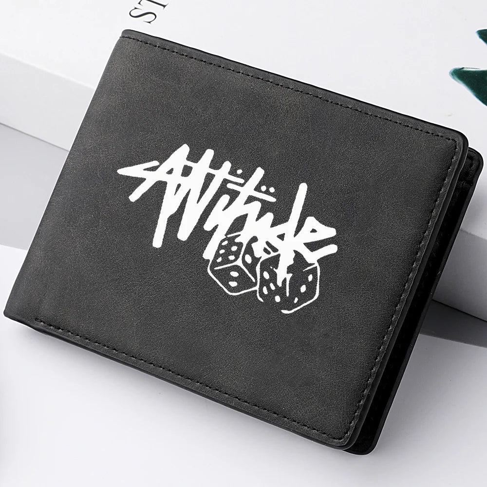 A black leather wallet with white stylized text and dice graphic lying on a white surface.