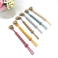 A collection of food-grade silicone pacifier clips with anti-lost chains in various pastel colors like pink, yellow, and blue