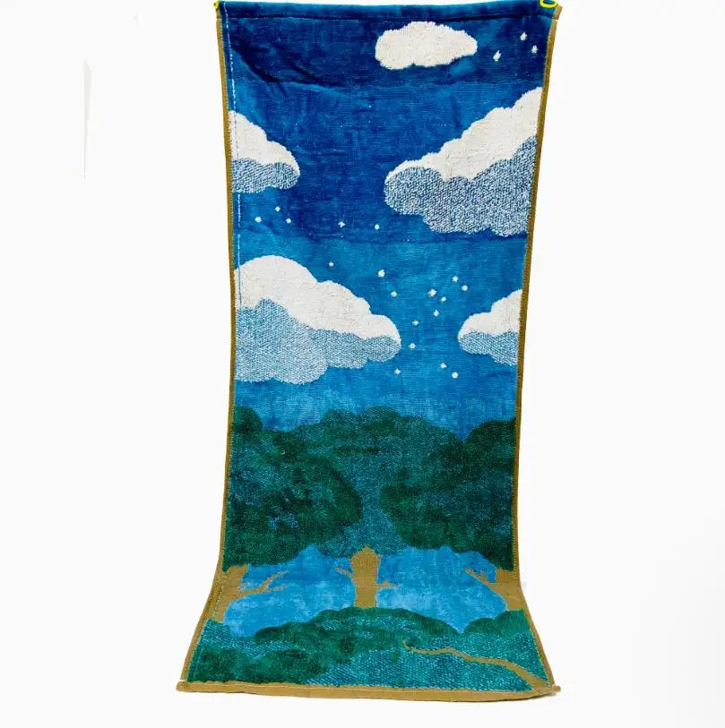 A deep blue towel featuring a sky scene with white clouds and green landscape silhouettes.