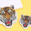 A detailed embroidery patch featuring a fierce tiger head with yellow eyes and striped fur on a yellow background.