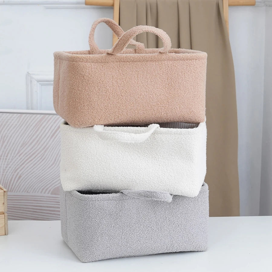 A set of three beige and gray fabric storage boxes for organizing baby items like diapers and bottles.