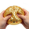 A hand holds a golden, squishy dumpling-shaped fidget toy for stress relief.