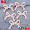 Five light pink embroidered cartoon bow iron-on patches displayed on a denim fabric.