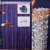 Purple crystal beaded string curtain hanging with a white sign that reads LIVE
