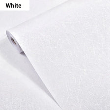 Roll of white embossed silk self-adhesive wallpaper being unrolled.