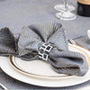 A navy blue patterned fabric napkin tied with a decorative metal ring on a white plate.