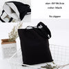 Black foldable canvas tote bag shown with an interior view and natural greenery.