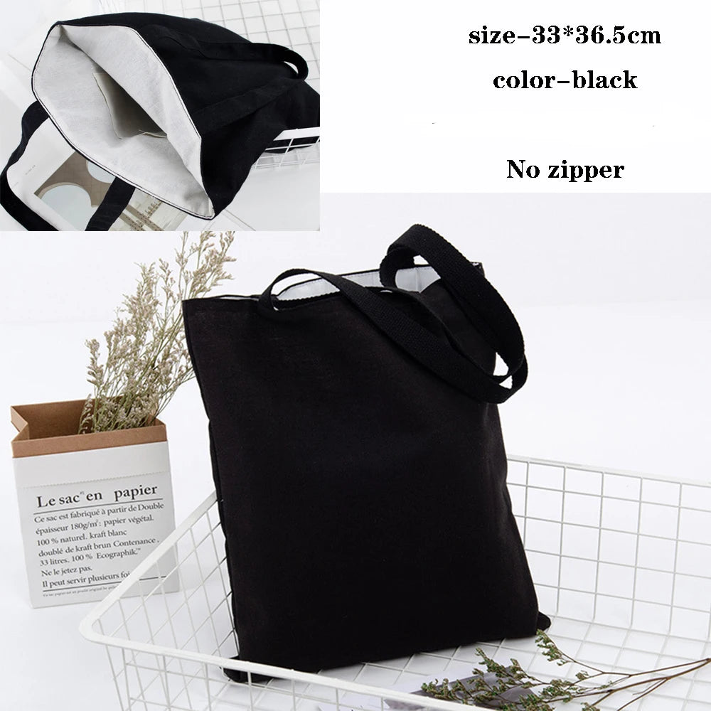 Black foldable canvas tote bag shown with an interior view and natural greenery.