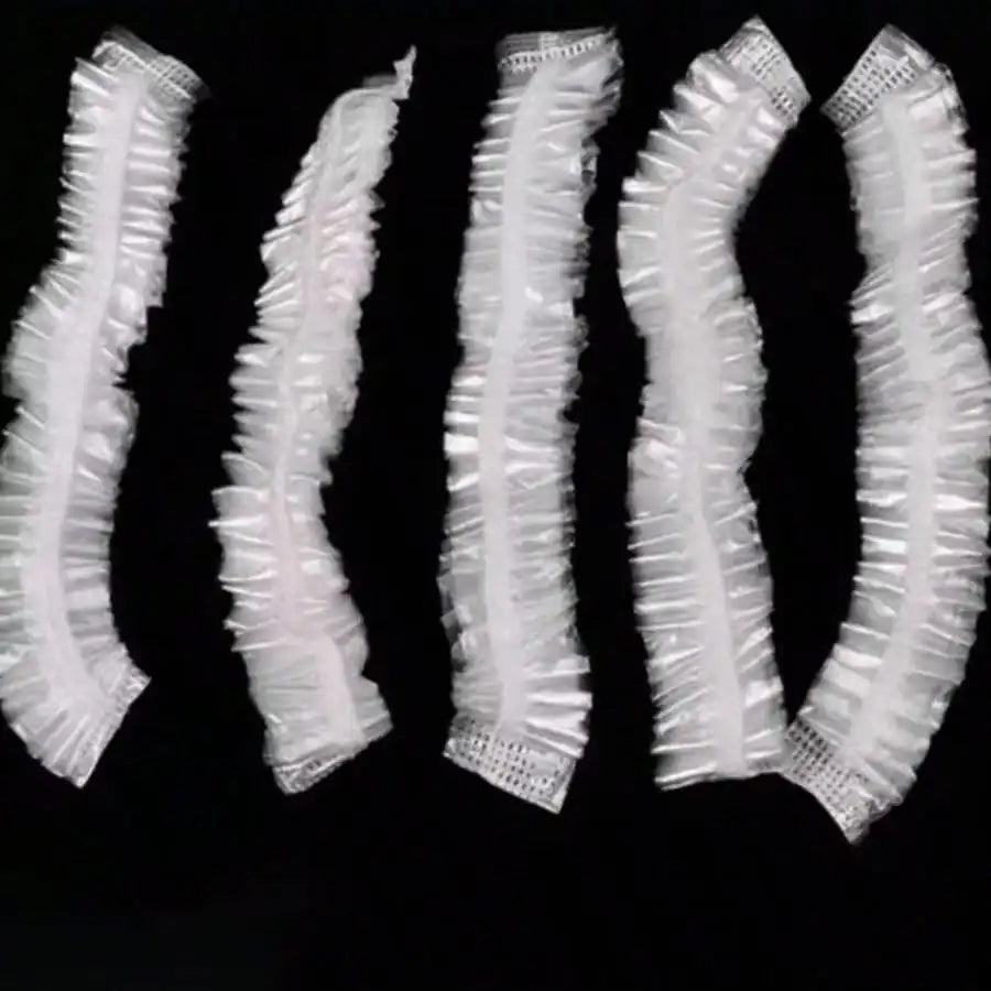 A pack of disposable transparent shower caps arranged in a row.