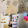 A collection of twelve gold heart-shaped refrigerator magnets arranged in rows.