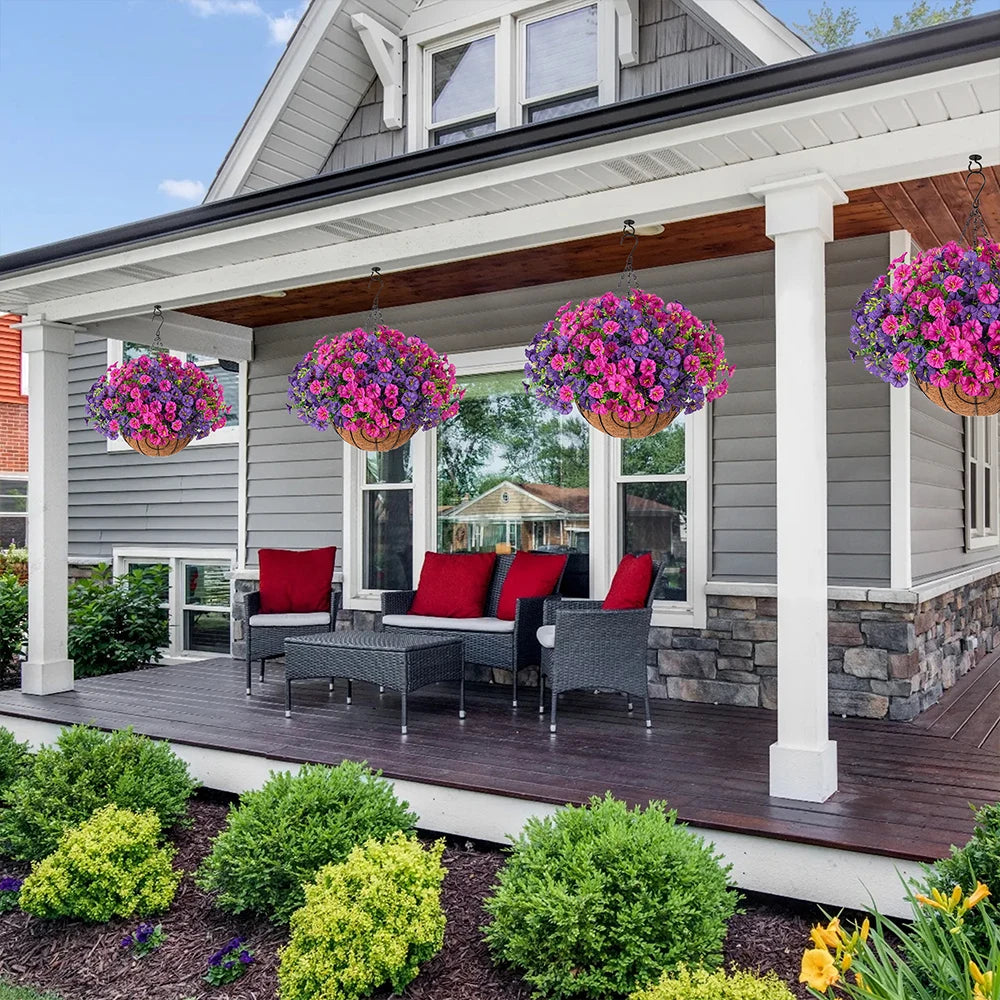 Artificial hanging morning glory flowers in a basket displayed on a wooden deck next to a house.