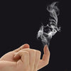 A hand is blowing smoke from a piece of chemical smoke magic paper against a dark background.