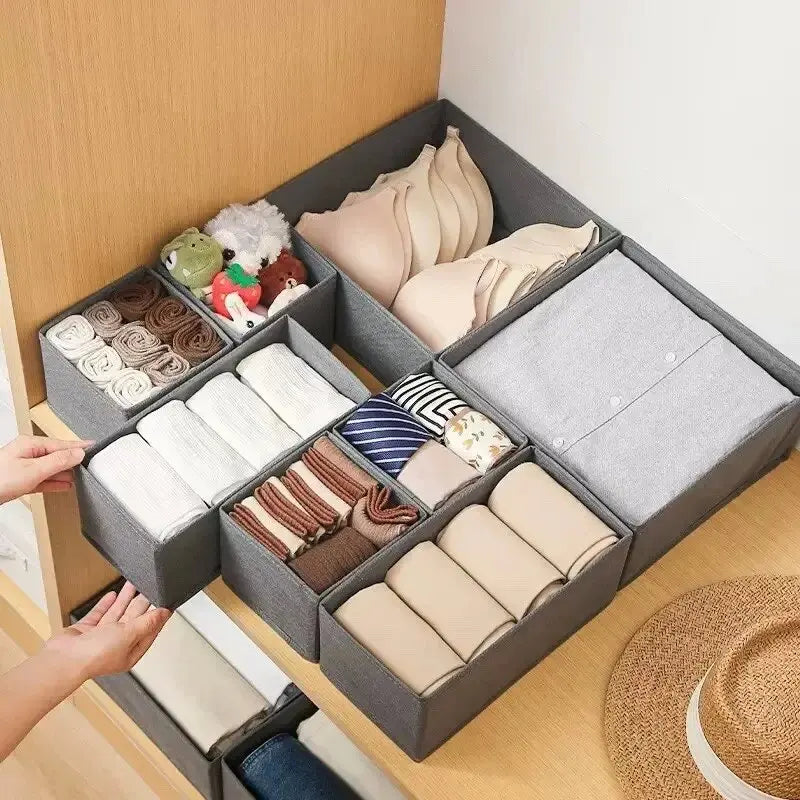 Gray drawer organizer boxes filled with folded underwear, bras, and socks.