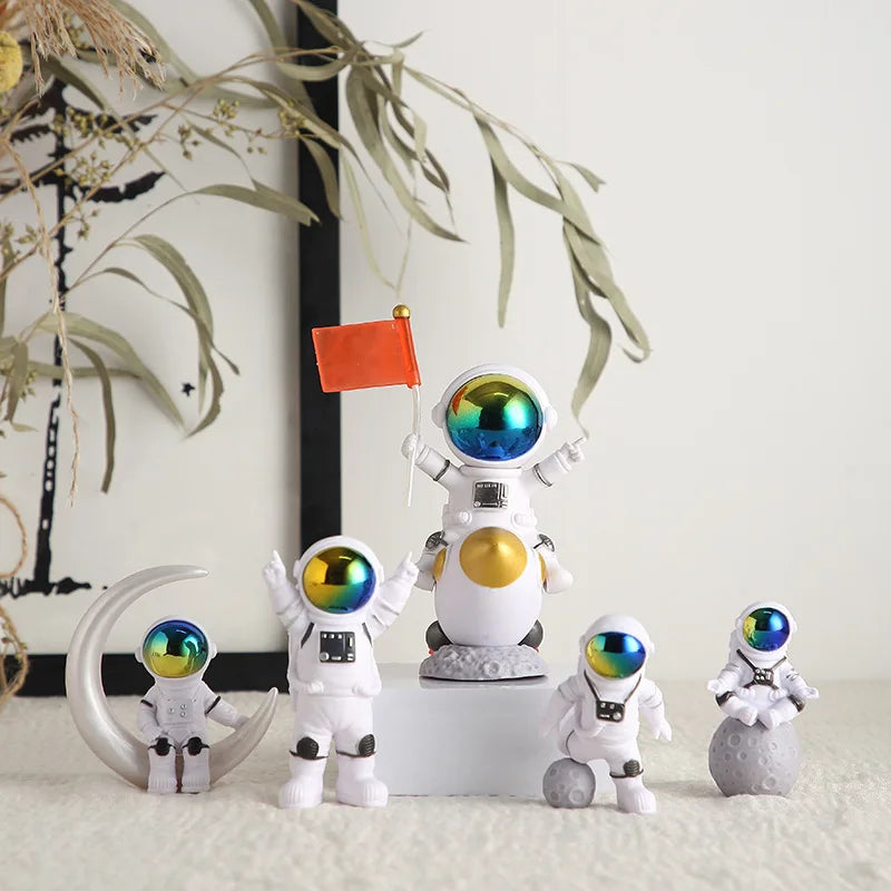 A collection of handcrafted astronaut figurines in white and silver on a white pedestal with a small orange flag.