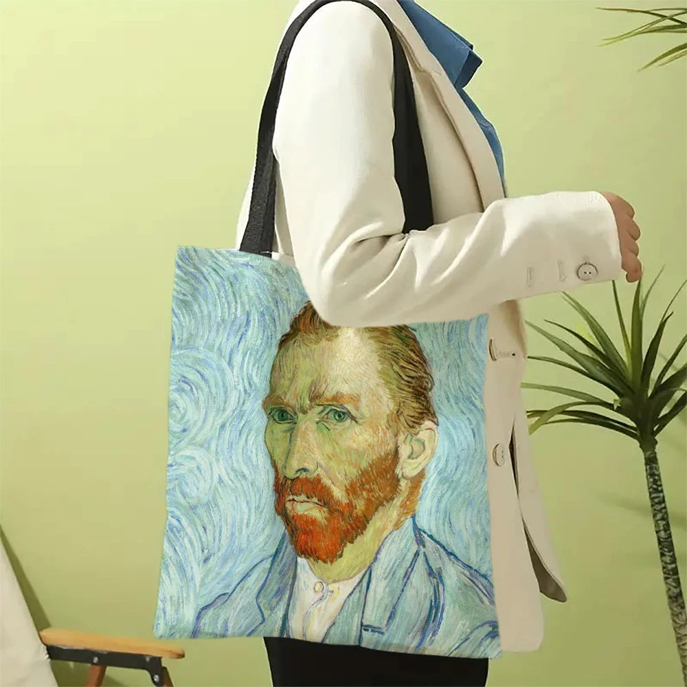 A person holds a canvas tote bag featuring a painting of Vincent van Gogh's portrait.