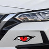 Close-up of a white car headlight with a black cat eye emblem featuring a red iris.