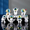 A collection of handcrafted astronaut figurine resin spacemen desk decor displayed on a black surface.